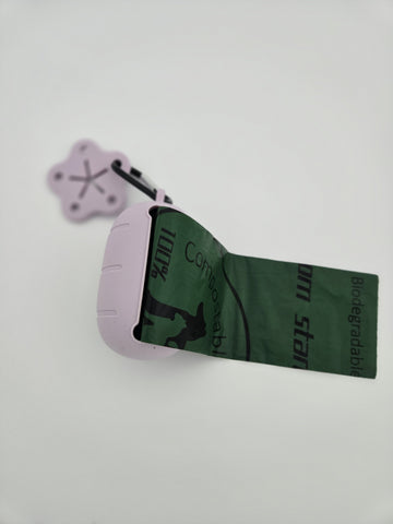Pink silicone dog poop bag dispenser with carabiner clip and paw charm includes compostable 15 bag roll and 99% recycled 15 bag roll, shows bag pulled out - thumbnail