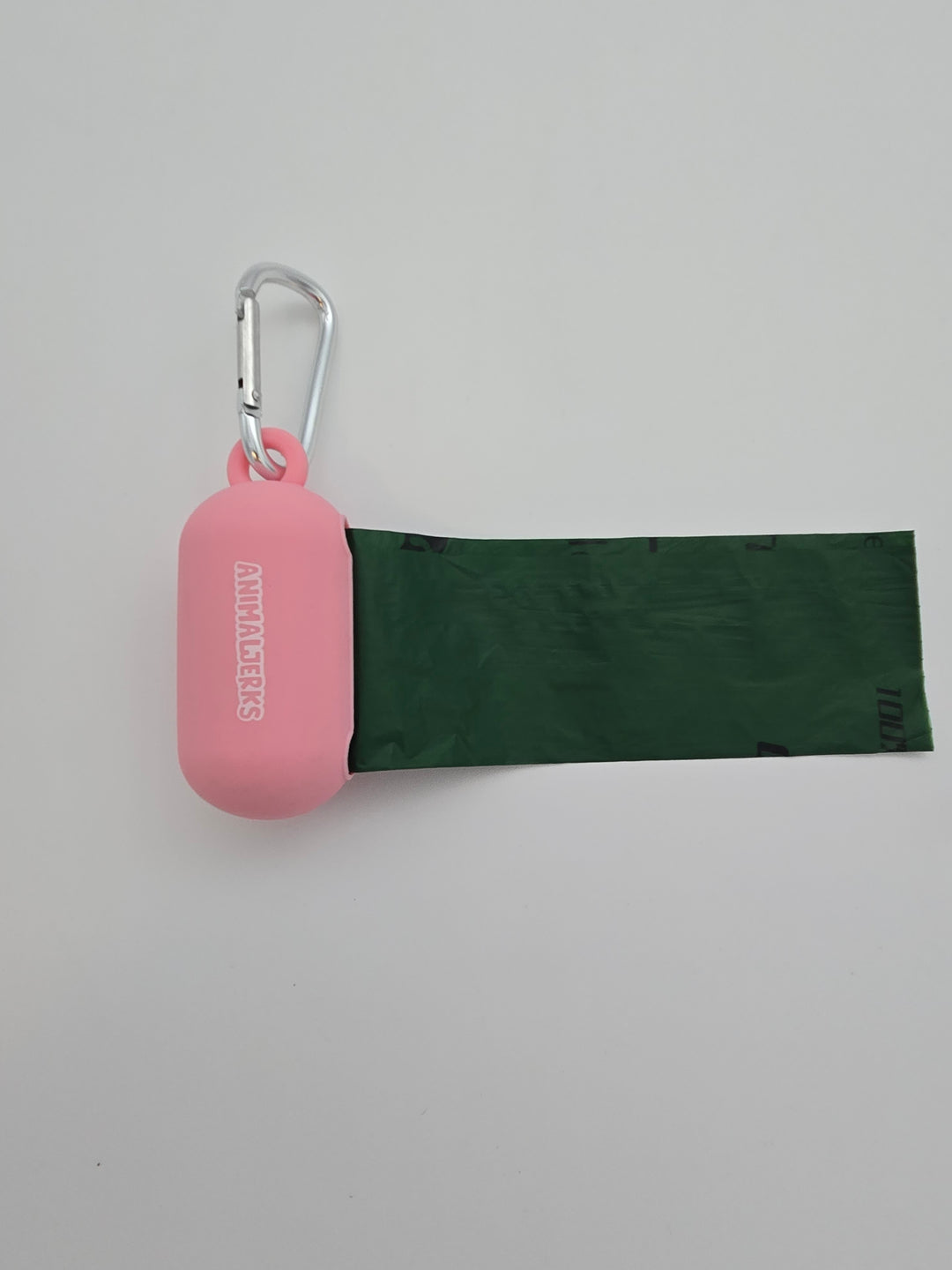 Pink portable food grade silicone dog waste bag dispenser with clip comes with compostable and recycled rolls, shows bag pulled out