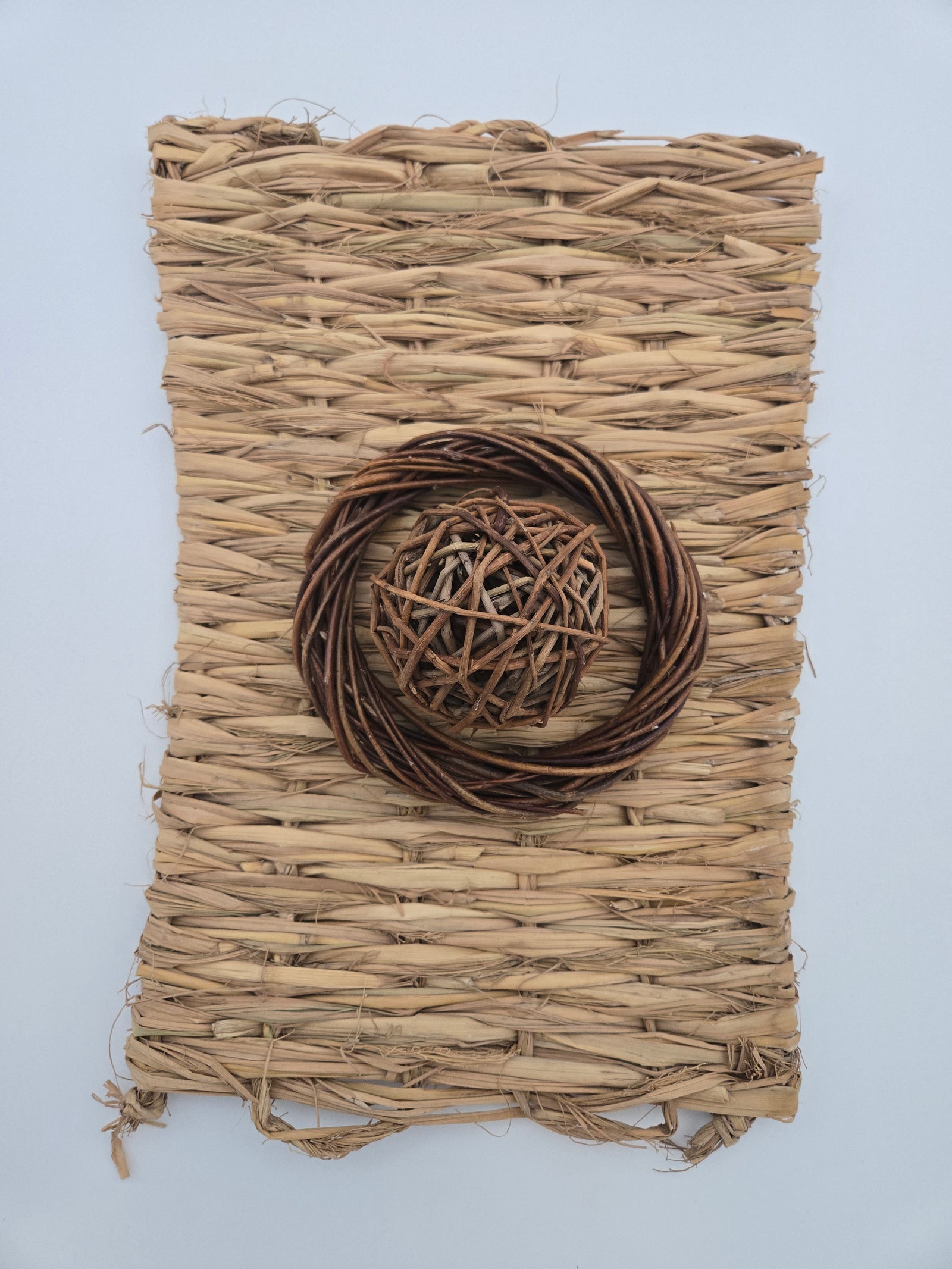 Woven grass matt 11 inches x 15 inches with a willow 6 inch halo sitting on the matt and a willow 2.5 inch ball inside the halo