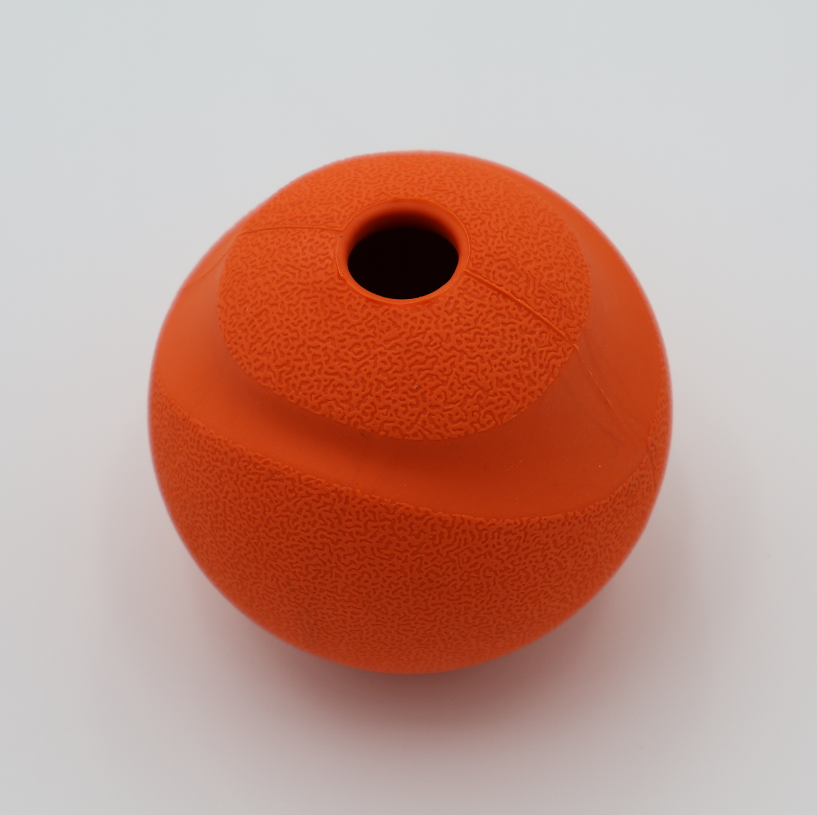 Orange treat dispensing dog ball with whistle sound food-grade silicone showing treat dispensing hole