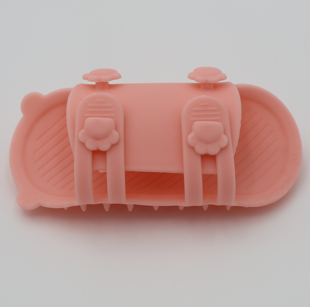 Pink silicone cat grooming scratcher, underneath showing the two sizes if it was attached to a table leg. 