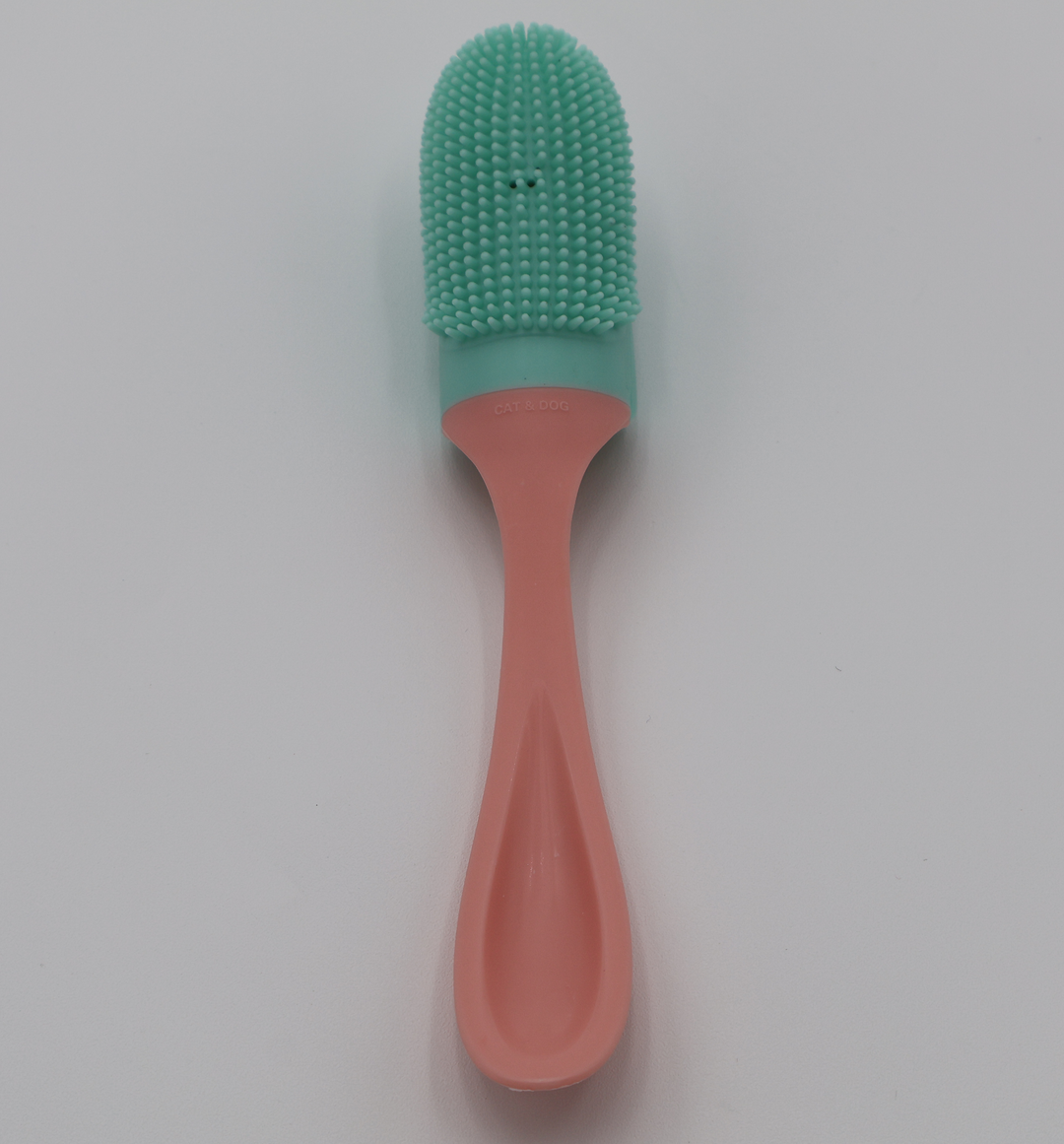 Pet toothbrush with  mint green silicone bristle head and ergonomic pink plastic handle 